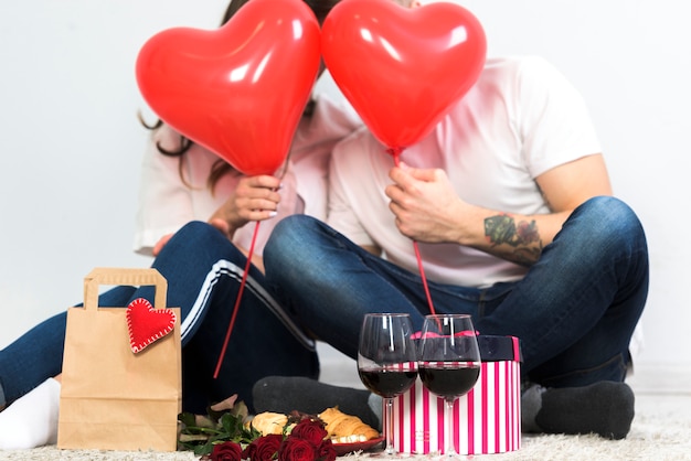 Free photo couple covering faces with red heart balloons