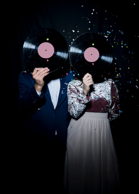 Free photo couple covering faces with vinyl records on party