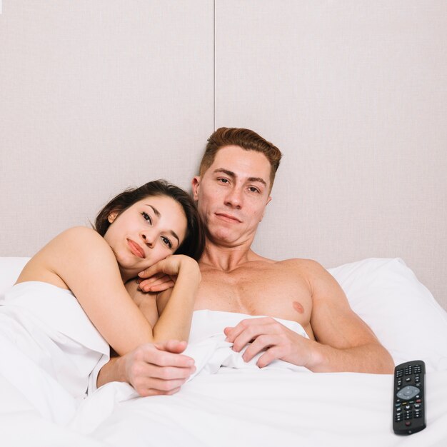 Couple cuddling in bed while watching tv