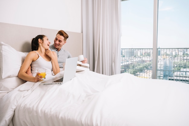 Free photo couple cuddling and laughing in bed in morning