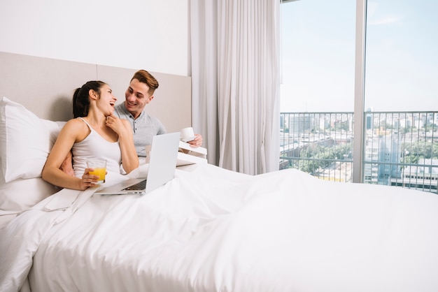 Couple cuddling and laughing in bed in morning