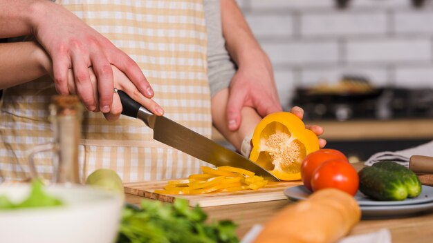 Couple cutting pepper in kitchen together