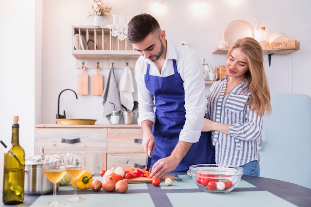 Free photo couple cutting pepper for salad on wooden board