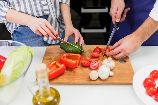 Free photo couple cutting vegetables on wooden board