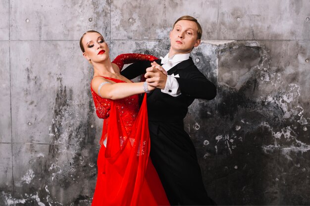 Couple in dance pose near gray wall