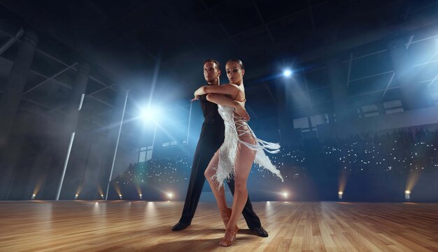 Пара танцоров исполняют латинский танец на большой профессиональной сцене