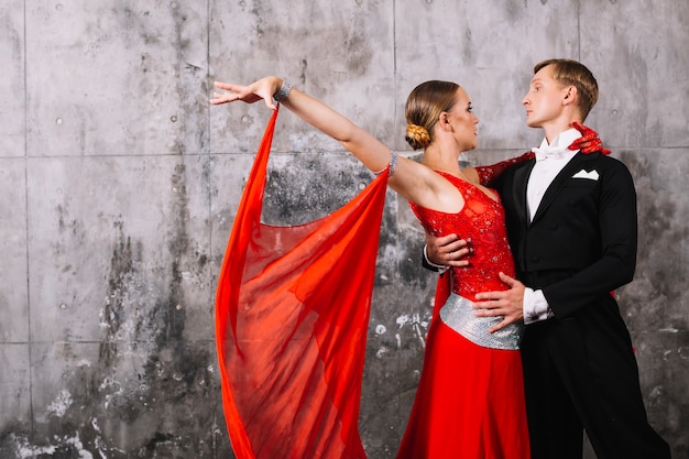 Free photo couple dancing passionate dance near gray wall