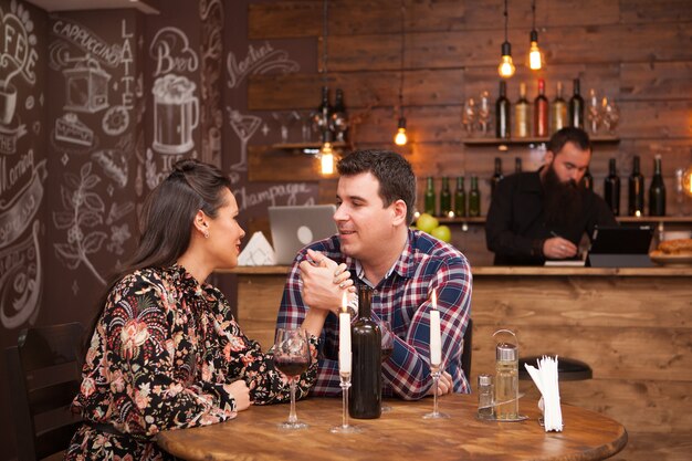 赤ワインを飲みながら流行に敏感なパブに座ってデートのカップル。お祝い 。