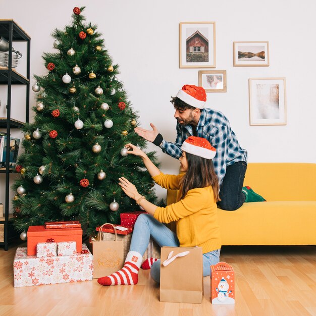 Couple decorating christmas tree at home