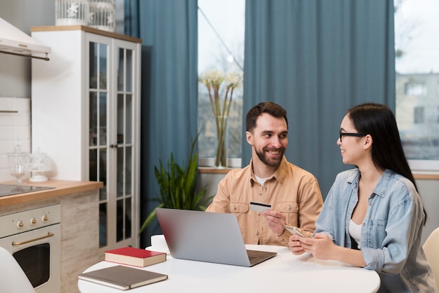 Free photo couple at desk holding smartphone and credit card