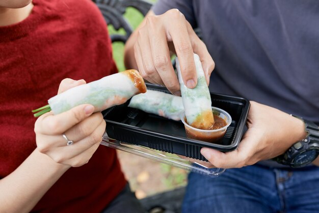 Couple dipping spring rolls in sauce
