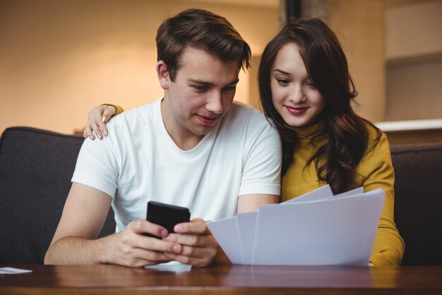 Couple discussing with financial documents and calculator in living room