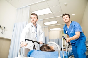 Couple of doctors using a gurney to transport a female patient to an operating room during an emergency