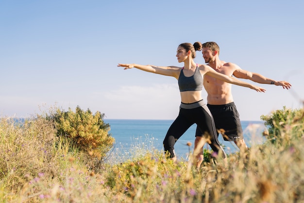 Free photo couple doing balance exercise at the beach