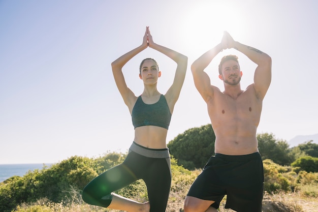 Пара делает упражнения йоги на солнце