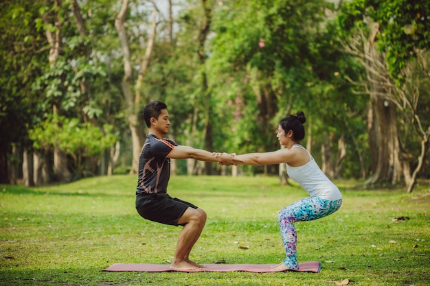 Couple doing yoga surrounded by trees