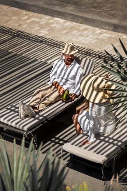 Coppia che beve latte di cocco a bordo piscina durante le vacanze