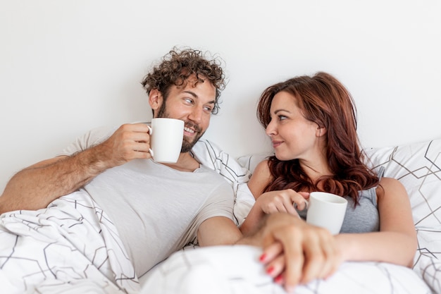 Free photo couple drinking coffee in the bed