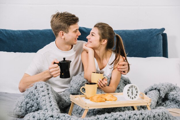 カップルがベッドの中でコーヒーを飲む 無料の写真
