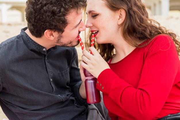 Free photo couple drinking from bottle with straws