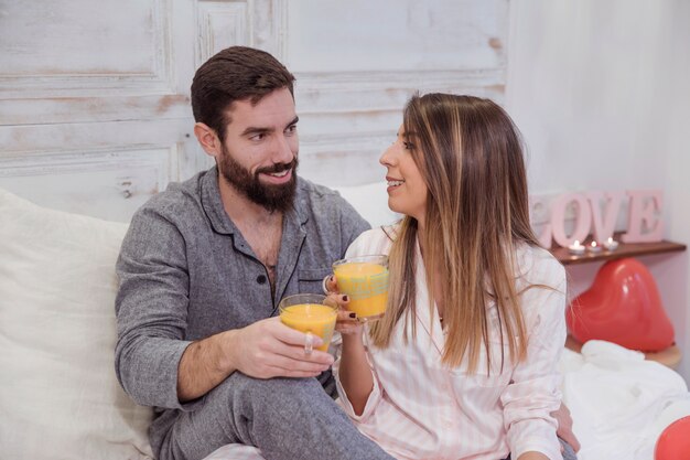 Couple drinking juice on bed 