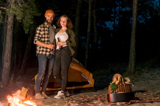 Free photo couple drinking and looking at the campfire