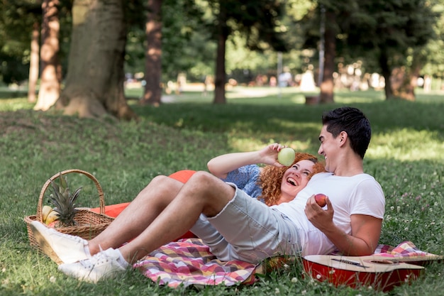 Couple eating apples together in the park