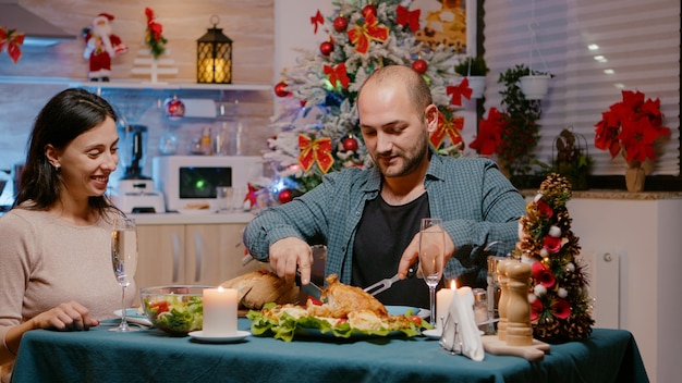 Couple eating chicken at festive dinner on christmas eve