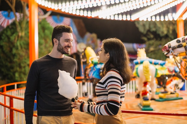 Couple eating cotton candy in a theme park