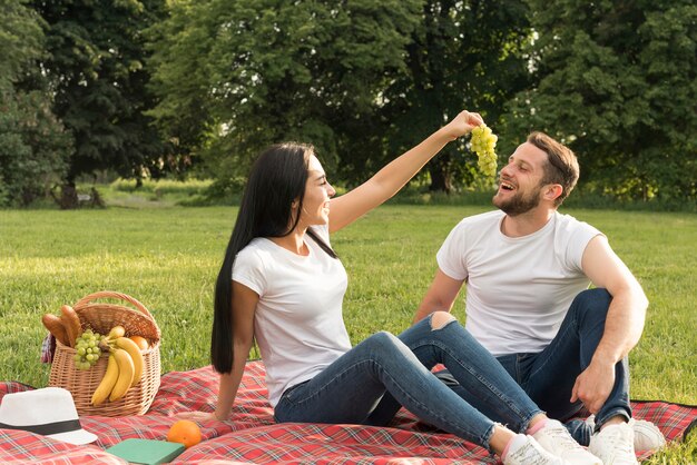 Couple eating grapes con a picnic blanket
