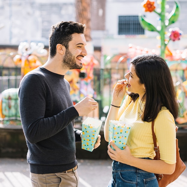 Foto gratuita coppie che mangiano popcorn in un parco a tema