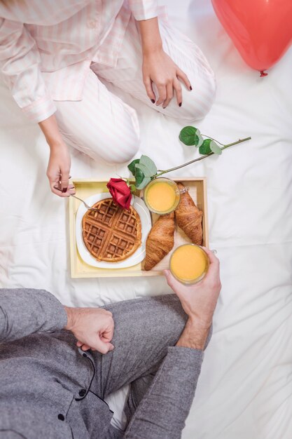 Couple eating romantic breakfast on white bed