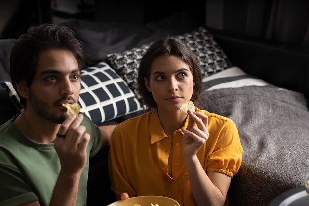 Free photo couple eating together at home on the sofa