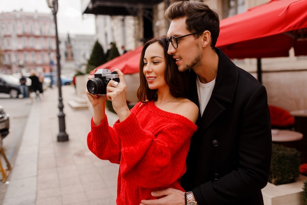 couple embarrassing and posing on the street on holiday. Romantic mood. Lovely brunette woman holding film camera.