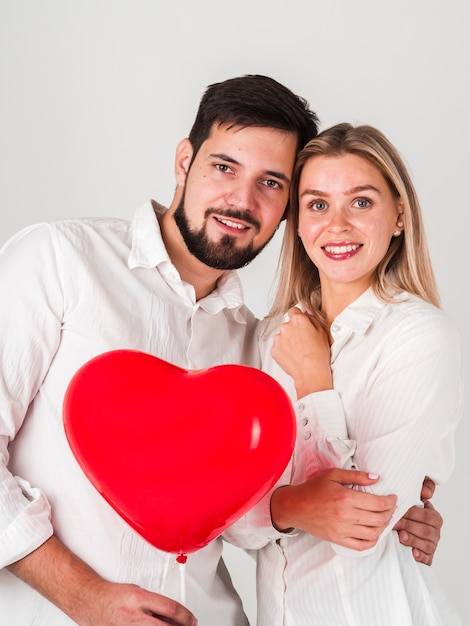 Free photo couple embraced holding valentines balloon