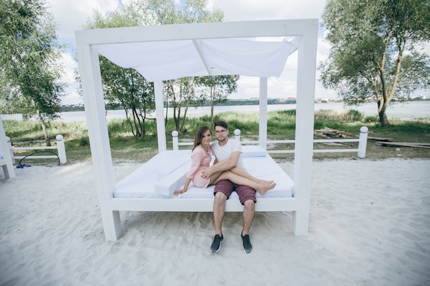 Foto gratuita coppie che abbracciano su un letto matrimoniale in spiaggia