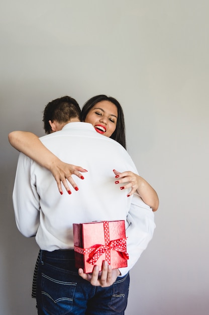 Couple embracing and groom with a gift in the back