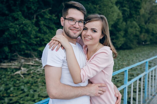 Couple embracing leaning on a blue fence on a bridge