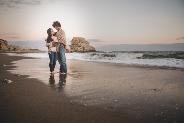 Couple embracing on the shore of the beach holding a candle