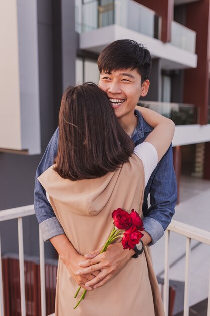 Couple embracing on the street and man holds a rose