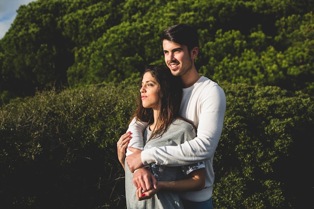 Couple embracing with a forest with trees behind