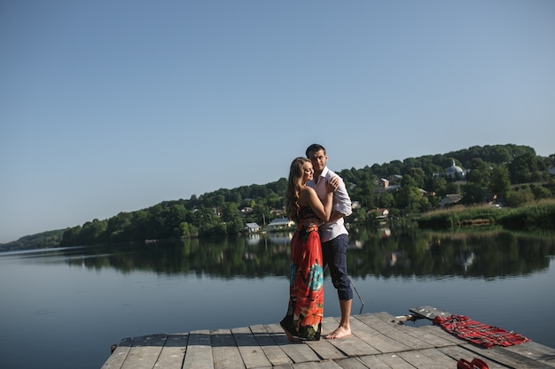 Free photo couple embracing with a lake and a mountain background