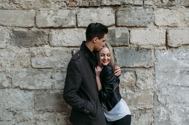 couple embracing with a large brick wall behind