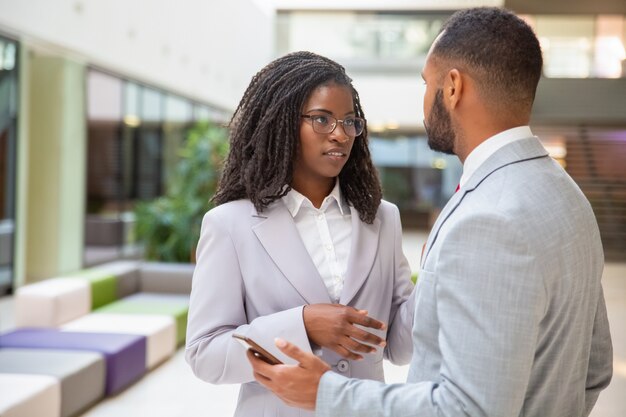 Couple of employees talking in office hall