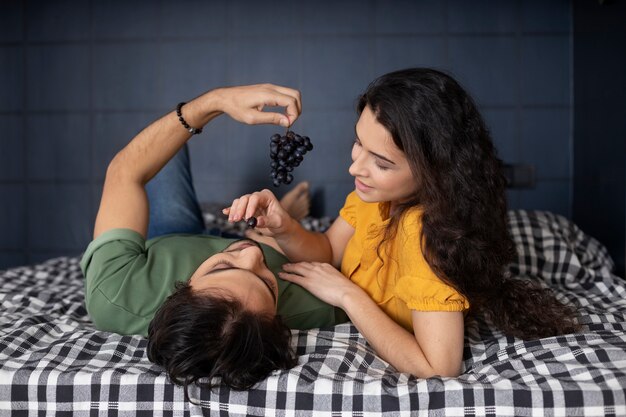 Бесплатное фото Пара, наслаждаясь виноградом вместе дома в постели