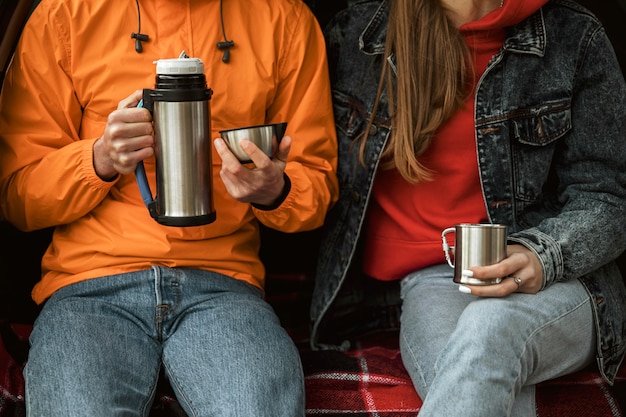 Couple enjoying hot beverage in the trunk of the car