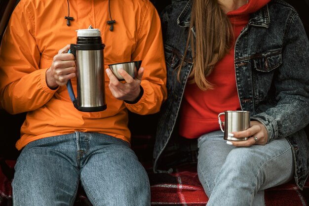 車のトランクで温かい飲み物を楽しむカップル