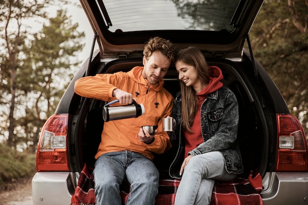 Couple enjoying hot beverage while on a road trip