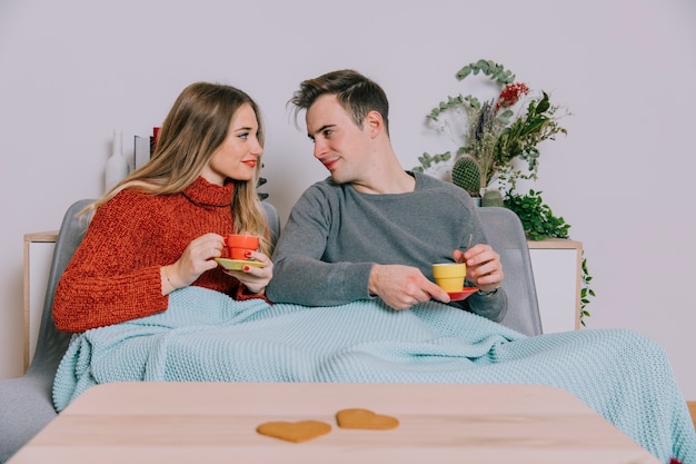 Couple enjoying hot drinks on sofa