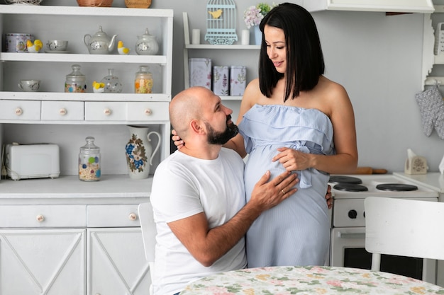Free photo couple expecting a baby staying in the kitchen